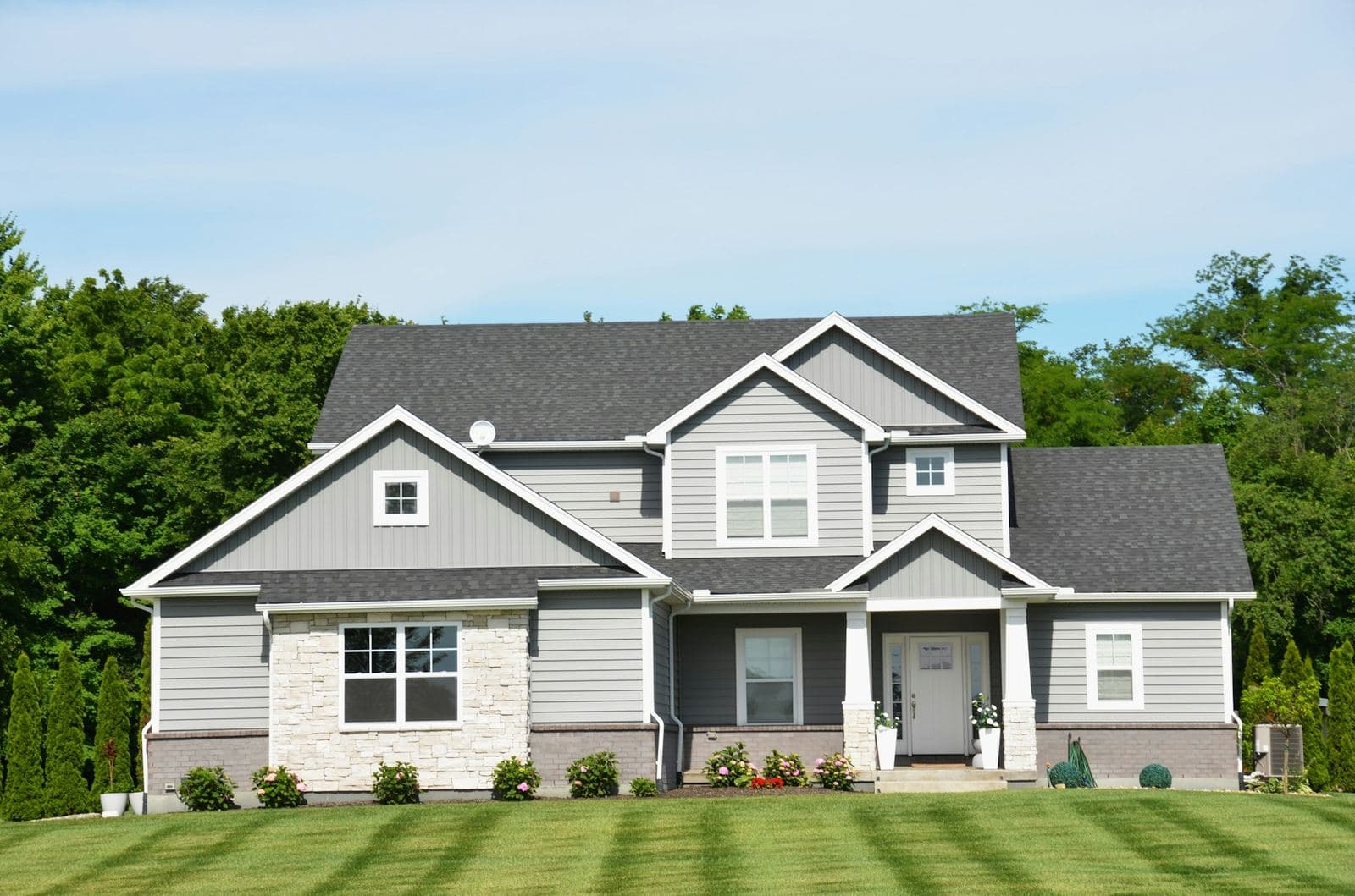 Two-story gray suburban home with a front porch and a freshly mowed lawn