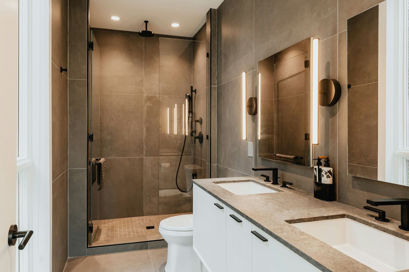 Remodeled bathroom with a double vanity and a tiled glass-door shower