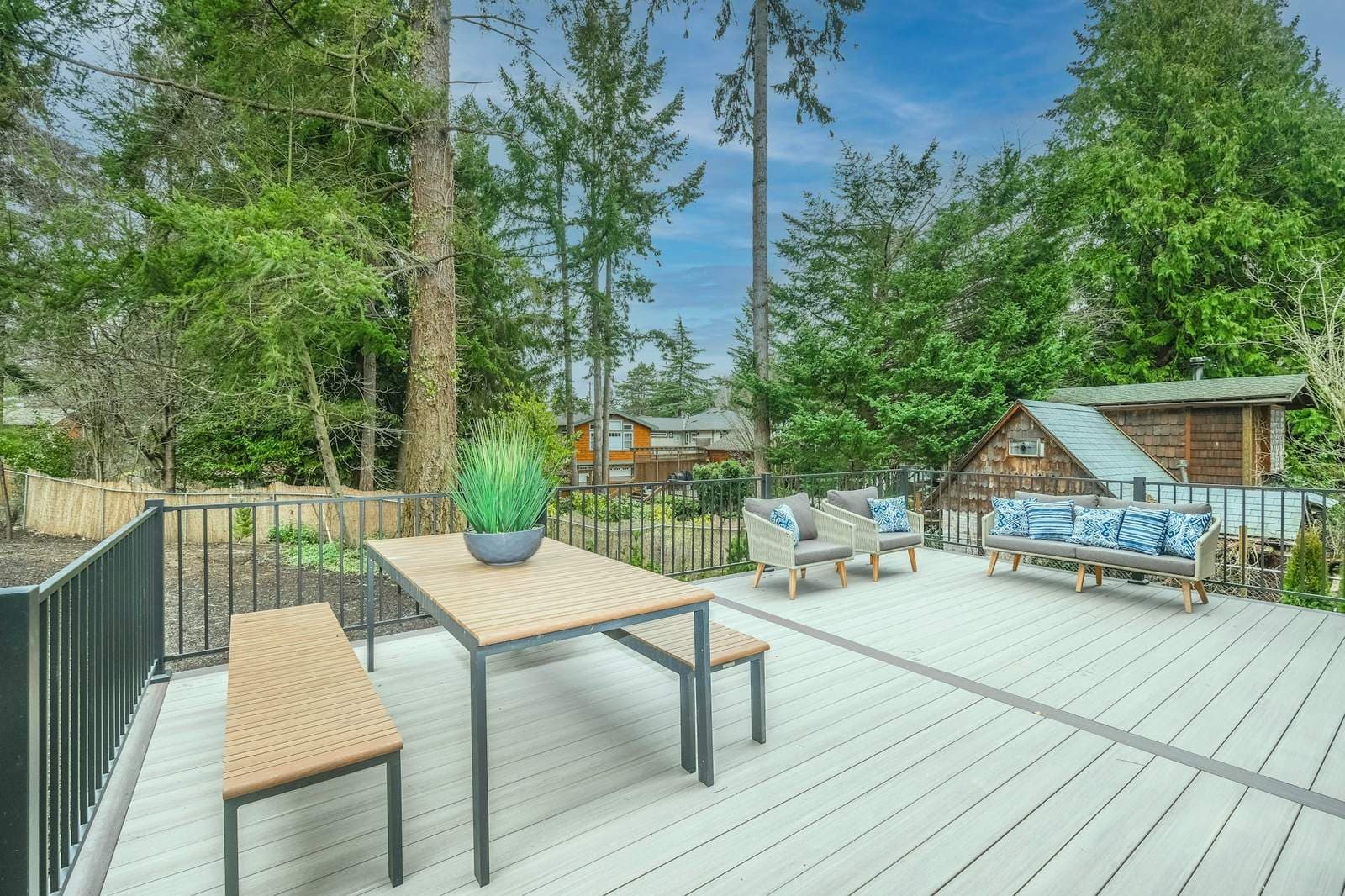 Large backyard deck with a table, benches and outdoor seating surrounded by trees