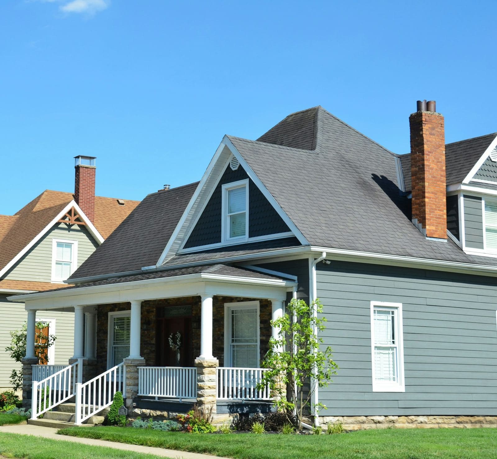 Blue-gray lap siding on a house with a white front porch and brick chimney