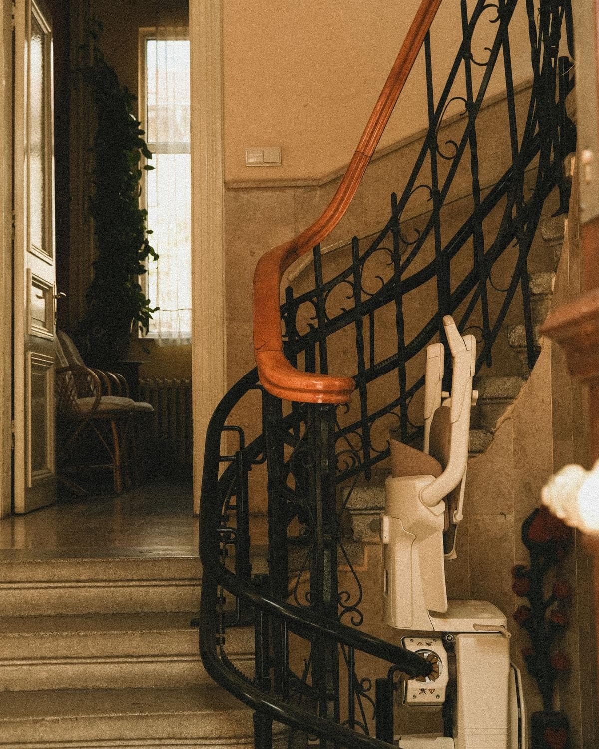 Stairlift chair mounted on a curved home staircase with a wooden handrail