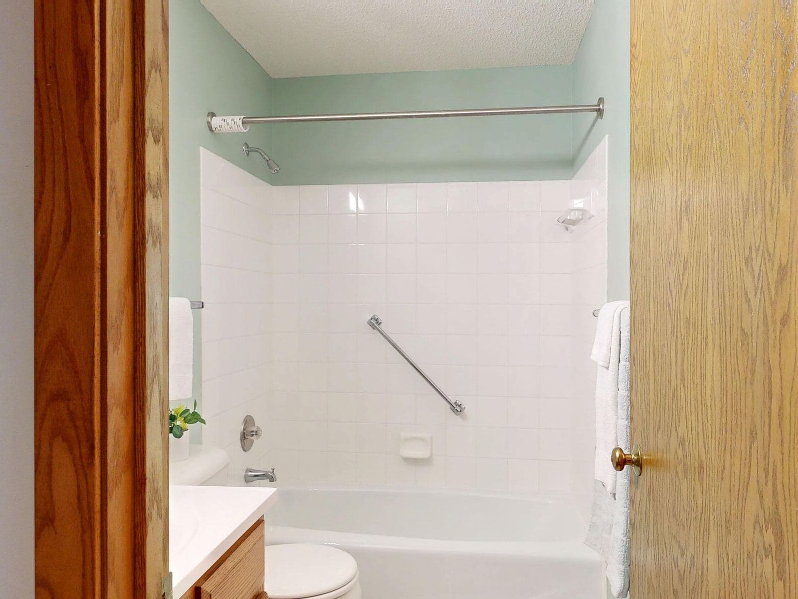 Bathtub with a safety grab bar on a white tiled wall