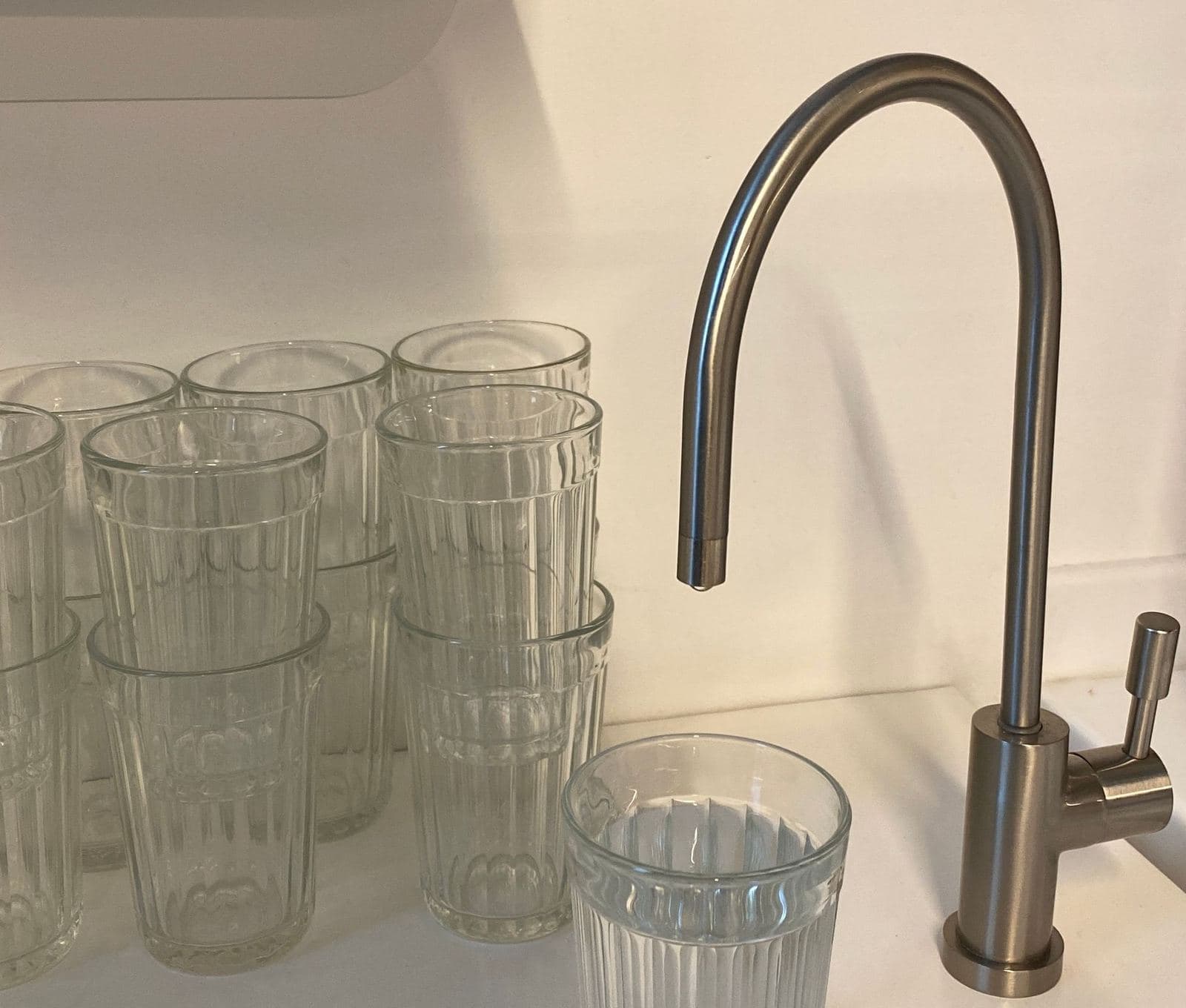 Filtered drinking water faucet on a counter next to clean glasses